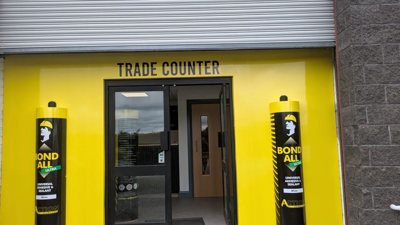 Action Adhesives trade counter shop front in bright yellow with two 5ft replica adhesive tubes flanking the entrance.