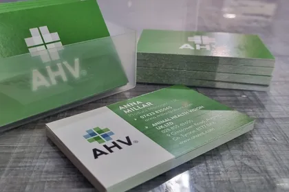 Animal Health Vision business cards printed in green and white, stacked on a desk.