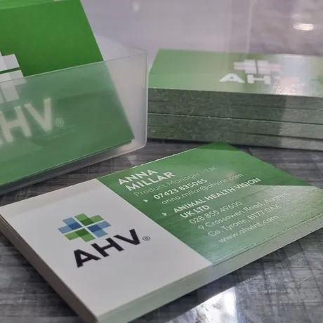 Animal Health Vision business cards printed in green and white, stacked on a desk.