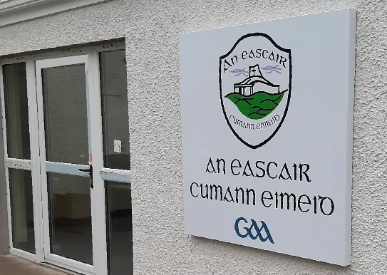 Eskra GAA composite aluminium club crest sign fixed to a rendered exterior wall.