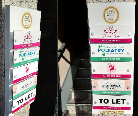 Stacked exterior building directory signs for several tenants, including Flower & Glow and a podiatry clinic.