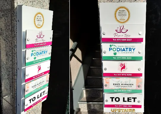 Stacked exterior building directory signs for several tenants, including Flower & Glow and a podiatry clinic.