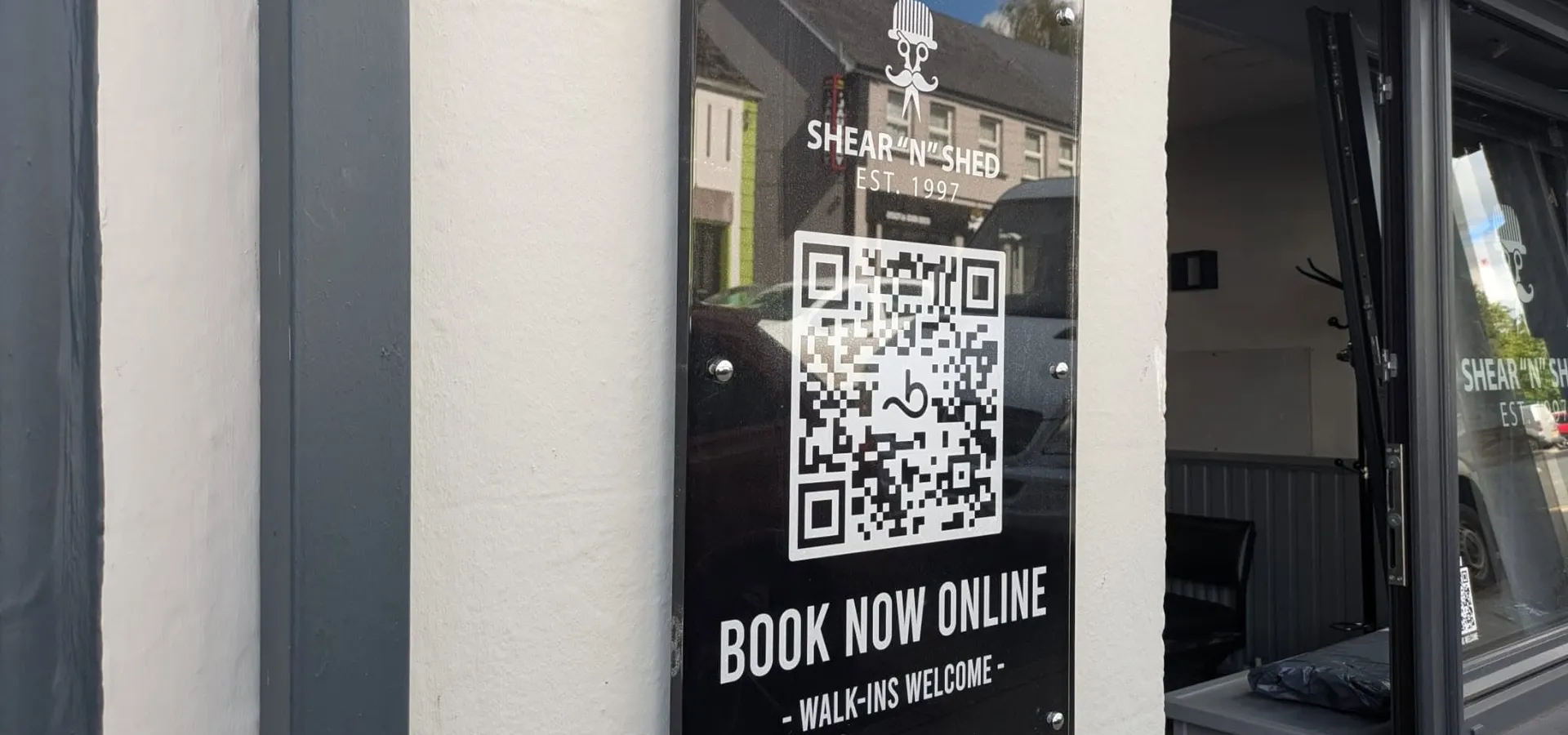 Black acrylic Shear 'n' Shed plaque with gold lettering and a QR code reading Book Now Online.